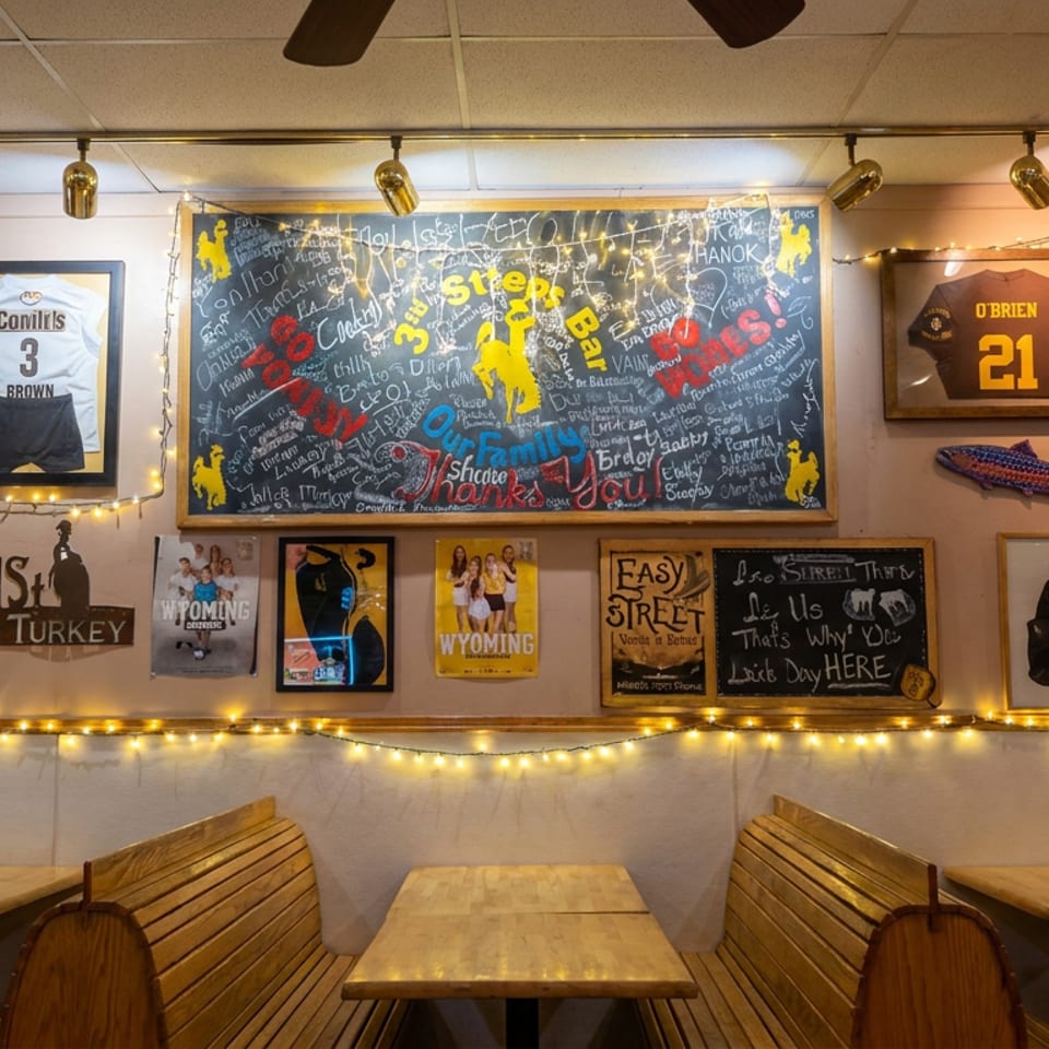 Cozy restaurant interior with wooden booths, sports memorabilia, chalkboard art, and warm string lights.